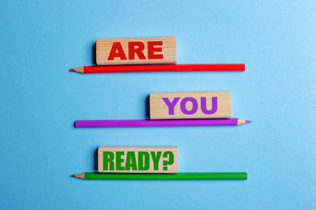 On a blue background, three colored pencils, three wooden blocks with text QUESTION ARE YOU READYの写真素材