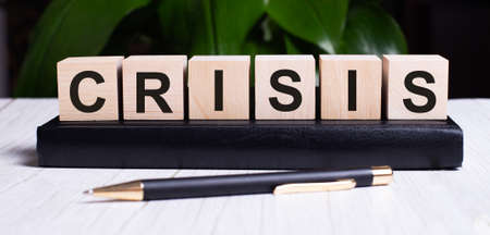 The word CRISIS is written on the wooden cubes of the diary near the handle.の写真素材