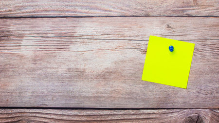 Blank yellow color sticker on wooden background. Copy space