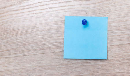 On a light wooden background, there is a blank square sticker for writing text. Template. Copy spaceの写真素材