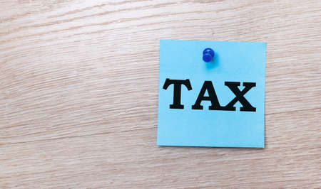 On a light wooden background - a light blue square sticker with the text TAXの写真素材