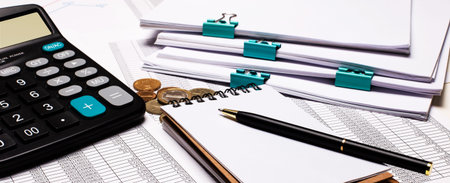 On the desktop are documents, a calculator, a pen, a notebook. Workplace close-up. Business concept
