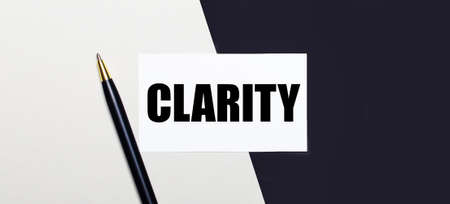 On a black and white background lies a pen and a white card with the text CLARITYの写真素材