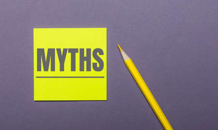 On a gray background, a bright yellow pencil and a yellow sticker with the word MYTHSの写真素材