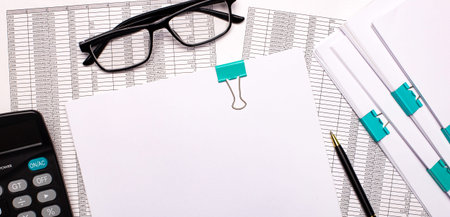 The desktop has reports, a calculator, a cash register, and a pen. Business concept. Workplace close...