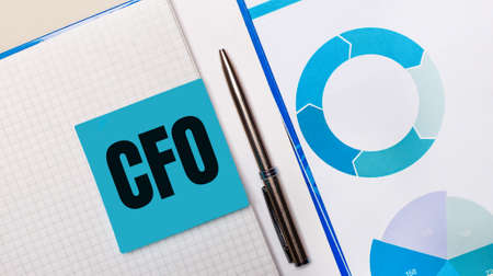 There is a pen between the blue sticky note with the text CFO Chief Financial Officer and the blue chart. Business concept. View from aboveの写真素材
