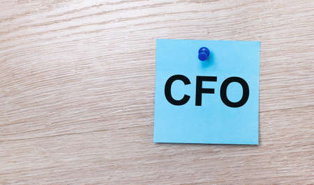 On a light wooden background - a light blue square sticker with the text CFO Chief Financial Officerの写真素材