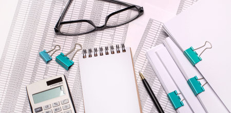 On the desktop are glasses, a calculator, a pen and a blank notebook with a place to insert text....