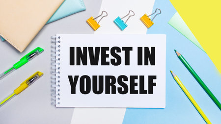 On a gray and blue background are stationery of yellow-green color, a notebook with the text INVEST...