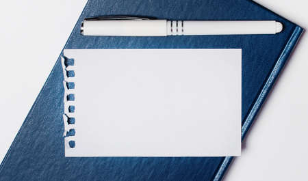 A blue diary lies on a light background. It has a white paper on it and a blank sheet of paper with space to insert text. Template. Copy spaceの写真素材