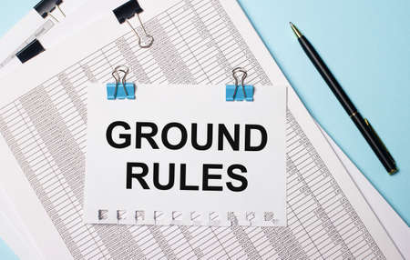 On a light blue background, documents, a pen and a sheet of paper on blue paper clips with the text GROUND RULES. Business concept.の写真素材