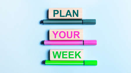 On a light blue background, there are three multi-colored felt-tip pens and wooden blocks with the PLAN YOUR WEEK text.の写真素材