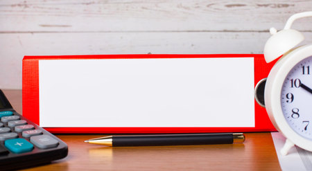 Red folder for papers with place to insert text, white alarm clock, calculator and pen on the...
