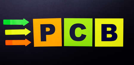 Bright multi-colored paper stickers on a black background with the text PCB Printed Circuit Boardの写真素材