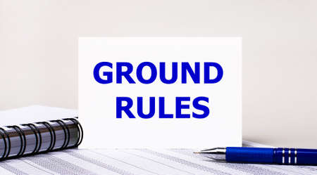 On a light gray background, a notebook, a blue pen and a sheet of paper with the text GROUND RULES. Business conceptの写真素材