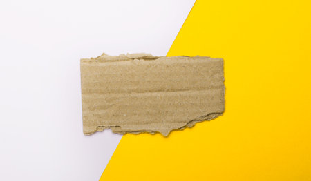 On a white and yellow background, brown torn cardboard with a place for text or illustration. Templateの写真素材