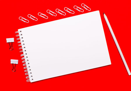 On a bright red background, a white pencil, white paper clips, white paper clips, and a white blank...