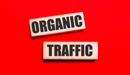 On a bright red background, there are two light wooden blocks with the text ORGANIC TRAFFICの写真素材