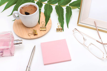 Flat lay, office desk, top view. Workspace with a coffee mug, an angry plant leaf, a perfume bottle,...