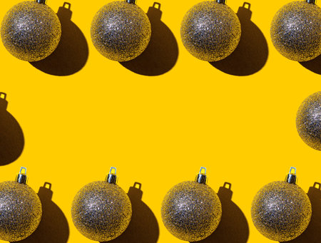 On a bright yellow background, a frame of Christmas gold balls with a place to insert the text....