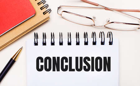On a light background - glasses in gold frames, a pen, brown and red notepads and a white notebook with the text CONCLUSION.Business conceptの写真素材