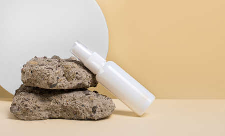 On a white-yellow background, natural raw light stones and a white clean bottle with a place to insert text. The concept of medicine and beauty. Mockupの写真素材