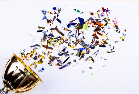 Golden prize cup with bright shiny multi-colored confetti on a light background.