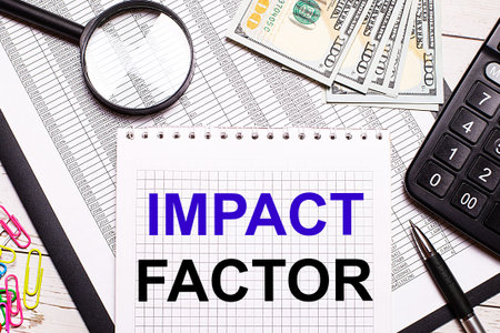 On the office table there is a notebook with the text IMPACT FACTOR, a pen, a calculator, dollars,...