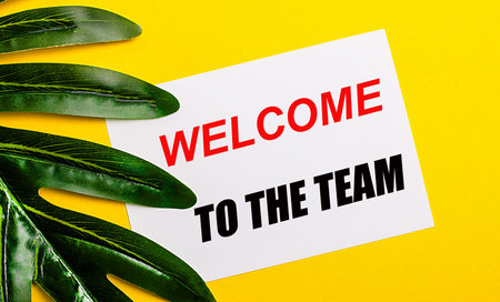 White sheet of paper with the inscription WELCOME TO THE TEAM on a bright yellow background near the...