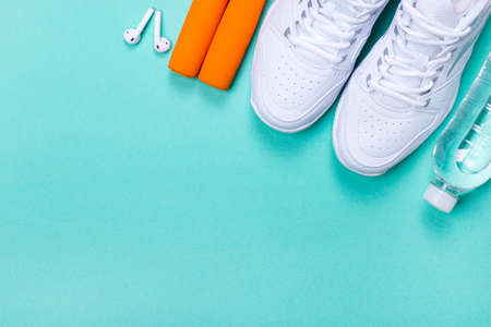 On a light green background, white sneakers, a bottle of water, a jump rope and headphones. The concept of a healthy lifestyle. copy spaceの写真素材