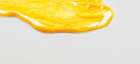 Transparent yellow smear of face cream or golden honey on a gray background. Golden creamy texture on a gray background.の写真素材