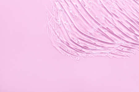 Facial serum or gel texture. Transparent skin care cream with bubbles background. Transparent cosmetic gel on a light pink background close-upの写真素材