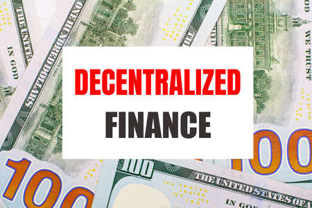 Against the background of American dollars, a white card with the DECENTRALIZED FINANCE. financial conceptの写真素材