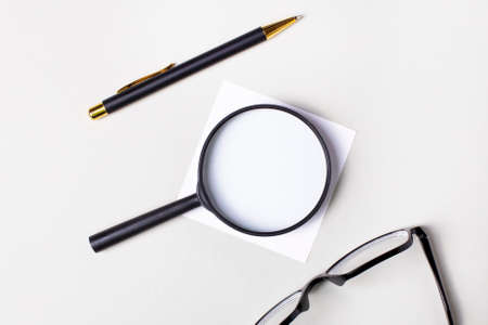 Black pen and glasses, black magnifier with a place to insert text on a light background. copy spaceの写真素材
