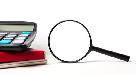 Office desk with notepads, black calculator, pen and magnifying glass with space to insert text....