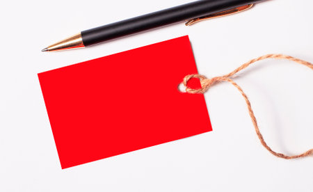 Red rectangular empty price tag with a place to insert text and a black pen on a white background. copy spaceの写真素材