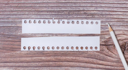 background for text. White strips of paper with empty space for text and a white pencil next to it on a wooden backgroundの写真素材