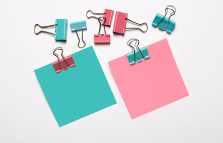 Colorful stickers with space to insert text and colorful paper clips on a white background