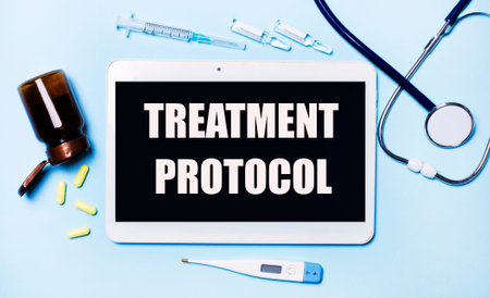 Ampoules, pills, stethoscope, thermometer, tablet with TREATMENT PROTOCOL text on desktop. Medical...