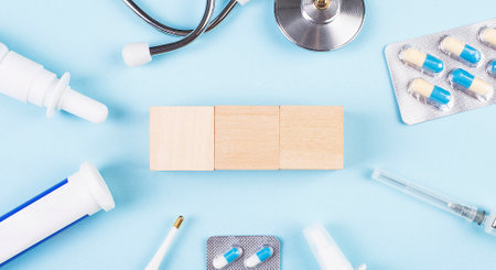 On a blue background, a stethoscope, a thermometer and other medicines and wooden cubes with a place to insert text. view from above. medical conceptの写真素材
