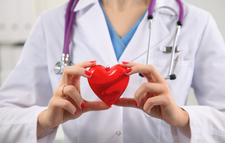 A doctor with stethoscope examining red heart .の写真素材