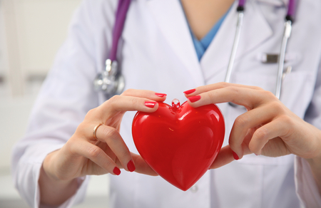 A doctor with stethoscope examining red heart .の写真素材