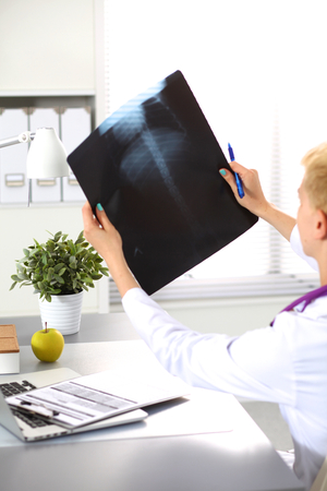 Portrait of young woman doctor in white coat at computer.の写真素材