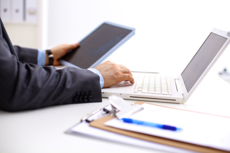Closeup of a businessman hands typing on a laptop keyboard.の写真素材