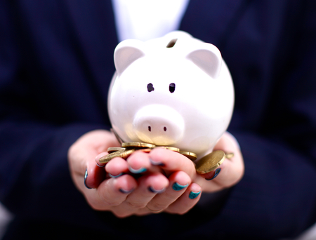 Businessman holding piggy box , standing in office .の写真素材