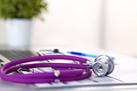A medical stethoscope near a laptop on a wooden table, on white.の写真素材