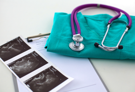 A stethoscope shaping a heart and a clipboard on a medical uniform, closeup.の写真素材