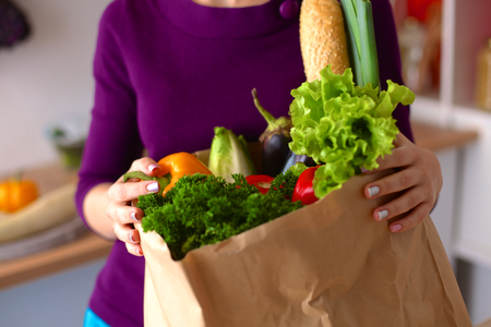 Healthy positive happy woman holding a paper shopping bag full of fruit and vegetables.の写真素材