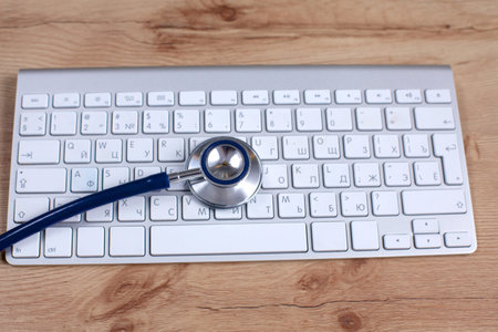 A medical stethoscope near a laptop on a wooden table, on white.の写真素材