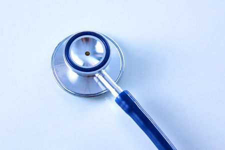 Medical violet  stethoscope lying in white backgroundの写真素材